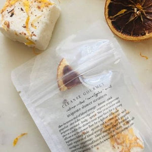A bag of shower steamers surrounded by dehydrated oranges and orange zest. 