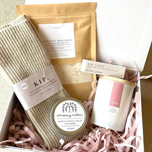 breast cancer support gift box for someone undergoing treatment for breast cancer featuring cashmere socks, coconut milk bath, hand salve, lip love lip balm and a cashmere candle