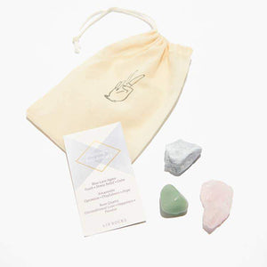 A small drawstring bag is displayed next to a set of three rocks and crystals. 